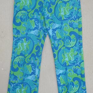 May include: A pair of vintage pants with a vibrant, swirling pattern in shades of blue and green. The pants have a straight leg cut and a high waist. The fabric appears to be a lightweight material, suitable for warmer weather.