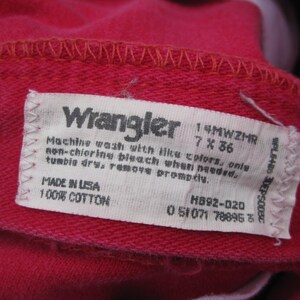 Peut inclure: Gros plan sur un tissu rouge avec une &eacute;tiquette blanche. L'&eacute;tiquette indique "Wrangler" et comprend des instructions de lavage et des informations de taille: 7 x 36 pouces (17,78 x 91,44 cm). Fabriqu&eacute; aux &Eacute;tats-Unis, 100% coton.