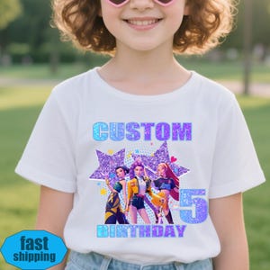 May include: White t-shirt featuring a vibrant graphic. The design includes the word "CUSTOM" in blue and purple, three cartoon figures, and the word "BIRTHDAY" with the number "5".