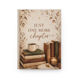 Peut inclure: Une couverture de livre avec le texte JUST ONE MORE chapter, un croissant de lune et des illustrations botaniques. En dessous, une tasse en céramique avec un cœur repose sur quatre livres empilés, près d'une bougie allumée et d'un livre ouvert.