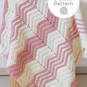 May include: A handmade crochet blanket with a chevron pattern in cream and light pink. The blanket is folded over a wooden storage container. The image includes a circular graphic that says "PDF Crochet Pattern".