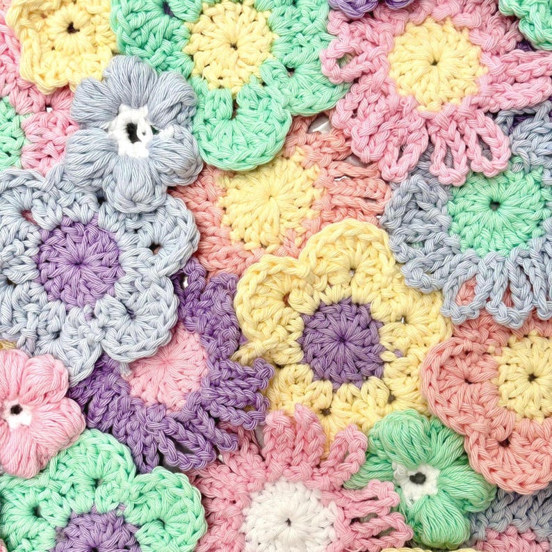 Puede incluir: Primer plano de una colecci&oacute;n de flores de ganchillo coloridas. Las flores son de varios colores pastel, incluyendo rosa, amarillo, azul, verde y morado. El trabajo de ganchillo es detallado, con cada flor teniendo un dise&ntilde;o de p&eacute;talo distinto.
