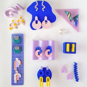 May include: Assortment of colorful polymer clay earrings displayed on blue and purple backgrounds. The earrings feature geometric shapes, abstract designs, and swirls.