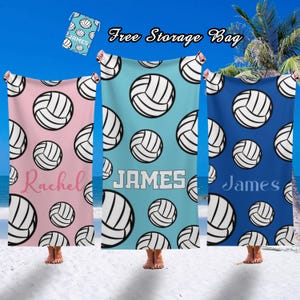 May include: Beach towels in pink, light blue, and dark blue, each featuring a repeating pattern of white volleyballs. The towels are personalized with names in white and pink. A small matching storage bag is included. Text on the image reads "Free Storage Bag".