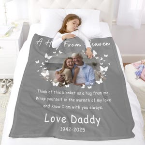 May include: A gray blanket with a photo of a man and woman, surrounded by butterfly graphics. Text reads "A Hug From Heaven" and "Love Daddy 1942-2025." The blanket also has a message about love and warmth.