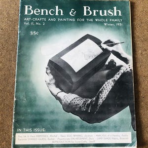 May include: A vintage magazine cover for "Bench & Brush: Art-Crafts and Painting for the Whole Family." The cover features a black and white photo of a person's hand drawing on a piece of paper. The magazine is from Winter 1951 and costs 35 cents.