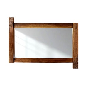 May include: A rectangular wooden mirror with a brown frame. The frame has a decorative pattern on the top and bottom corners.