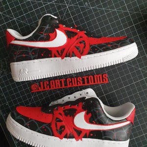 Puede incluir: Zapatillas rojas y negras personalizadas con detalles blancos. Las zapatillas presentan una suela blanca, un dise&ntilde;o rojo en la puntera y los laterales, y un logotipo de Nike blanco. El texto "AIR" es visible en la suela.