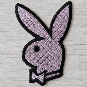 May include: A lavender embroidered patch featuring the iconic rabbit head silhouette with a bow tie. The design has a quilted diamond pattern texture throughout the lavender surface and is outlined with a thick, bold black stitched border.