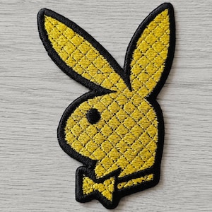 May include: An embroidered patch featuring the iconic rabbit head silhouette with a bow tie. The design is rendered in bright yellow thread with a quilted diamond pattern texture, outlined by a thick, solid black border for high contrast.