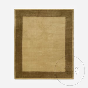 May include: A rectangular area rug with a solid light tan center and a darker brown border. The rug has a soft, plush texture and a simple, elegant design. The rug is suitable for living rooms and bedrooms.