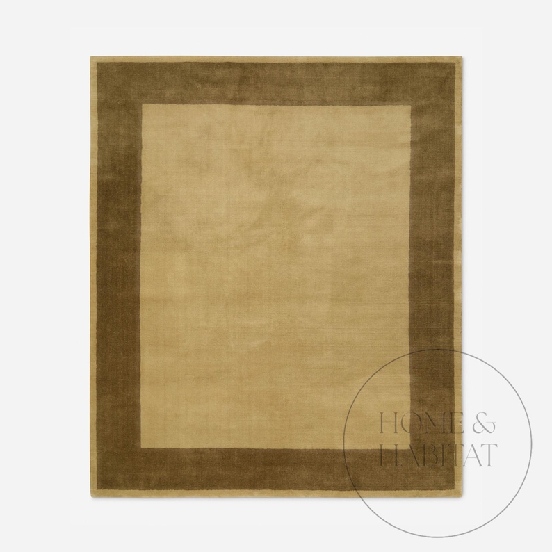 May include: A rectangular area rug with a solid light tan center and a darker brown border. The rug has a soft, plush texture and a simple, elegant design. The rug is suitable for living rooms and bedrooms.
