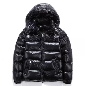 May include: A glossy black puffer jacket with a hood. The jacket has a full zipper closure, two front pockets, and a shiny, quilted appearance. The jacket is designed for cold weather.