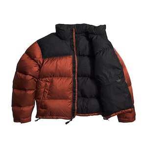 May include: A puffy, two-tone jacket in rust and black. The jacket has a high collar, a full-length zipper, and a pocket on the inside. The outer shell is a warm rust color, while the upper portion and interior are black.