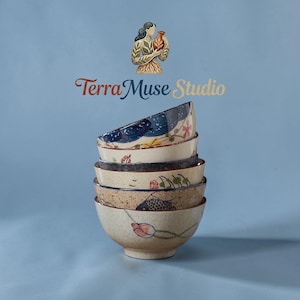 Puede incluir: Una pila de seis cuencos de cerámica con diseños pintados a mano, incluyendo peces, flores y patrones abstractos. Los cuencos son en tonos beige, azul y marrón. La imagen también presenta el texto "Terra Muse Studio" y una ilustración de una mujer sosteniendo un jarrón.