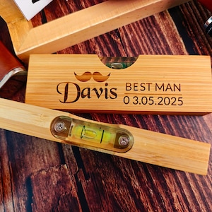 May include: A wooden level with a level bubble and a personalized message that reads "Davis Best Man 03.05.2025". The level is engraved with a mustache and the words "Best Man".