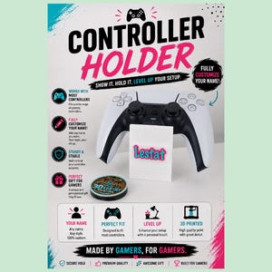 May include: A white 3D printed controller holder featuring the name Lestat in pink and blue text. The display includes text stating Controller Holder, Show it. Hold it. Level up your setup, Fully customize your name, and Made by gamers, for gamers.