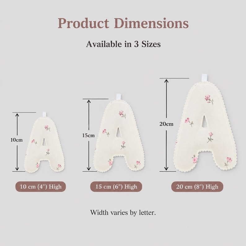 May include: Three off-white fabric letter A ornaments with a small pink floral pattern, featuring scalloped edges and a hanging loop. The image displays three sizes: 10 cm (4 inches), 15 cm (6 inches), and 20 cm (8 inches) in height.
