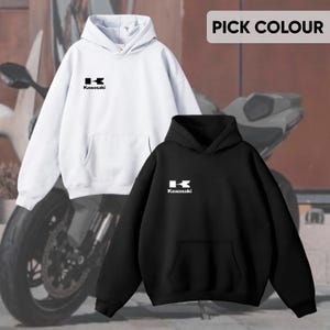 May include: Two hoodies, one white and one black, are displayed. Each features a front pocket and a hood. The Kawasaki logo is printed in white on the chest of each hoodie. The text "PICK COLOUR" is visible in the top right corner.