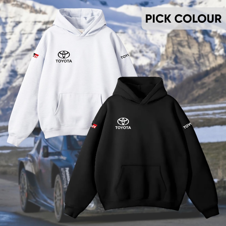 May include: Two hooded sweatshirts, one white and one black, featuring the Toyota logo and text. The white sweatshirt has a red and black GR logo on the sleeve. The black sweatshirt has a white Toyota logo. The text "PICK COLOUR" is at the top.