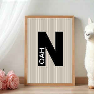 May include: A framed print with the name "NOAH" in black letters, with a beige and white striped background. A white stuffed llama stands to the right of the frame. Pink roses are in the lower left corner.
