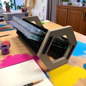 "Acrylic marker organizer with dual-angle stand on workshop desk"