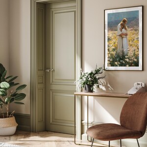 May include: Interior scene with a framed artwork depicting two figures embracing in a field of flowers. A brown chair, a table with a lamp and a telephone, and a potted plant are also visible. The walls are painted in neutral tones.