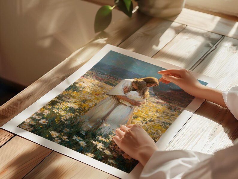 May include: A print of a painting depicting two figures embracing in a field of yellow and white flowers. The figures are dressed in white robes. The print is on a white background and is resting on a wooden surface.