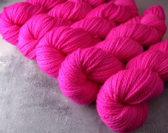 May include: A close-up of several skeins of bright pink yarn. The yarn is soft and fluffy, and it is perfect for knitting or crocheting.