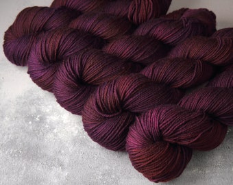 May include: Close-up of a deep burgundy yarn with a subtle color variation. The yarn is soft and textured, with a slight sheen.