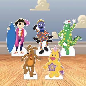 May include: Five colorful cardboard cutouts of cartoon characters. A pirate with a surfboard, an octopus in a checkered outfit, a green dinosaur, a brown dog, and a yellow unicorn with a star and the letter "S" on its chest.