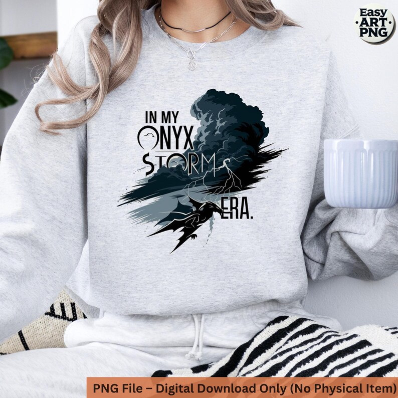 May include: A gray sweatshirt with a graphic design of a black storm cloud with lightning bolts and a dragon. The text "In My Onyx Storm Era." is printed on the sweatshirt.