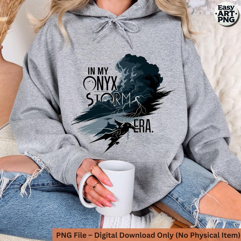 May include: Gray hoodie with a black and white graphic design featuring a dragon, lightning bolts, and the text "In My Onyx Storm Era."
