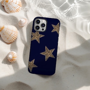 May include: A navy blue phone case featuring a pattern of leopard print stars. The case is resting on a bed of white sand, with several seashells scattered around it. The case has a glossy finish.