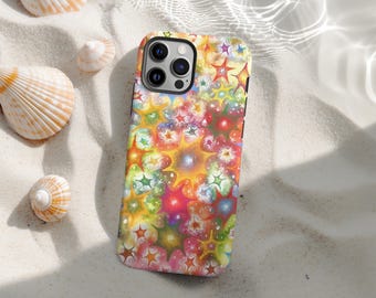 May include: A colorful phone case with a vibrant starburst pattern in shades of yellow, red, green, and blue. The case is lying on a sandy surface with seashells scattered around it. The phone case has a black camera module.