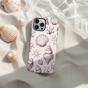 Peut inclure: Coque de téléphone blanche ornée d'un motif répété de coquillages roses, de coraux et d'étoiles de mer. Le motif présente divers types de coquillages, créant un thème côtier. L'image est posée sur du sable.