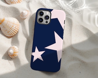 May include: A navy blue phone case with a pattern of large, light pink stars. The case is lying on a bed of white sand, surrounded by seashells. The phone case has a black camera module.