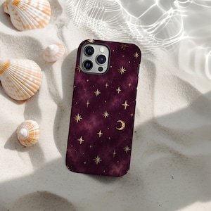 May include: A smartphone case featuring a deep burgundy, cloud-like background pattern adorned with gold-coloured celestial motifs, including various four-pointed stars and a crescent moon. The case has a cutout for a triple-lens camera system.