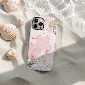 Pode incluir: Uma capa de telefone com padrão floral com um design de patchwork em tons de rosa, branco e creme. A capa apresenta uma variedade de estampas florais, xadrez vichy e um coração. A capa do telefone é cercada por conchas em uma superfície arenosa.