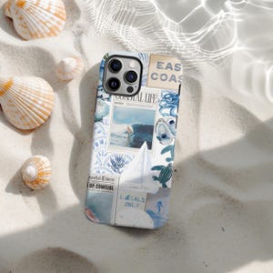 May include: A phone case with a coastal theme, featuring a collage of blue and white images. The design includes a surfer, seashells, a sailboat, and the text "Coastal Life" and "East Coast". The case is on a sandy surface with seashells.