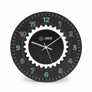 May include: A white ceramic mug with a black handle and the text "But First, Coffee" in a black, handwritten-style font. The mug is on a white surface.