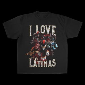 Puede incluir: Camiseta negra con un diseño gráfico. El texto "I LOVE LATINAS" está en una fuente texturizada. El diseño presenta personajes de dibujos animados con acentos rojos y negros y rayos.