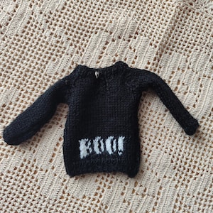 May include: Black knitted sweater with long sleeves and a white "BOO!" design on the front.