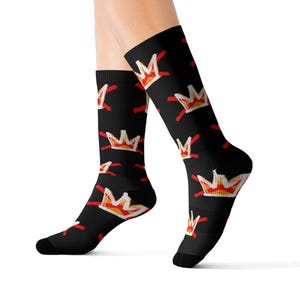 May include: Black knee-high socks with a repeating pattern of stylized crowns in red, yellow, and white. The socks are made of a soft, comfortable material and are suitable for various occasions.
