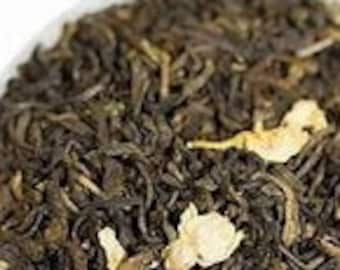 May include: A bowl of loose leaf green tea with white flower petals. The tea is a blend of green tea and jasmine.