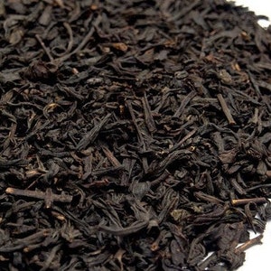 May include: Close-up of loose-leaf black tea. The tea leaves are dark brown and black, with a slightly textured appearance. The tea is likely used for brewing a beverage.
