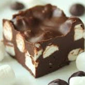 Puede incluir: Un trozo cuadrado de fudge de chocolate con malvaviscos blancos en su interior. El fudge es brillante y tiene un color marrón intenso.
