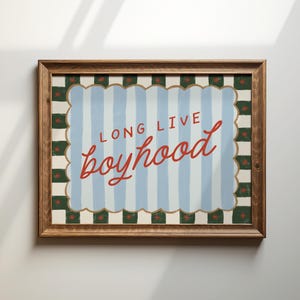 Puede incluir: Una impresión artística enmarcada con las palabras "LONG LIVE boyhood" en escritura roja. El fondo presenta rayas verticales azules y blancas, enmarcadas por un borde festoneado con acentos verdes y rojos, todo dentro de un marco de madera.
