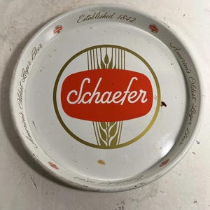 May include: Vintage Schaefer beer serving tray. The white tray features a red and gold logo with the name "Schaefer" and the text "America's Oldest Lager Beer". The tray is round and has the text "Established 1842".