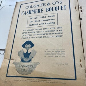 May include: A vintage Colgate & Co. advertisement for Cashmere Bouquet soap. The ad, with a blue border, features text and an illustration of a woman. The text includes the phrase "Of All Toilet Soaps the Most Luxurious, Refined and Lasting." Established 1806.